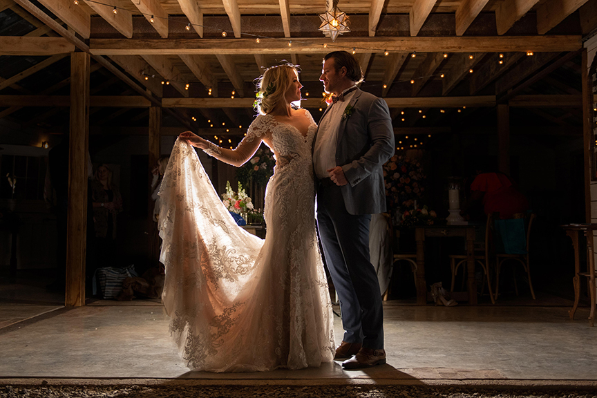 stunning wedding photo with light behind the couple, beautiful wedding dress glows from the light inside the venue