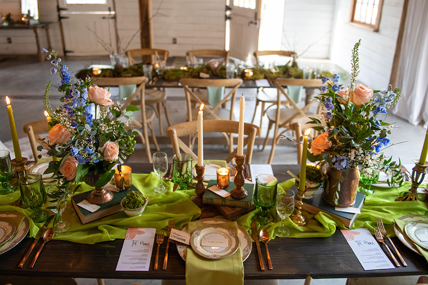 A spring green wedding table setting, with brass candlesticks, mismatched china, vintage books and stunning florals
